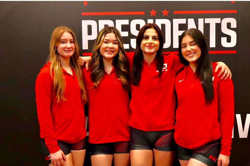 W&J women’s wrestling team members posing in front of a Presidents backdrop